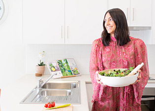 Woman in kitchen holding salad